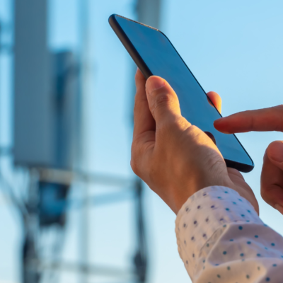 Mobile phone being used with cell tower in background