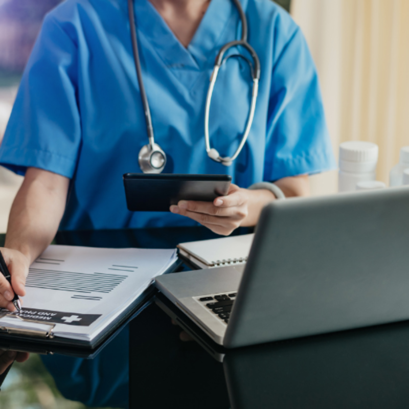 Anonymous doctor using laptop and phone while writing note