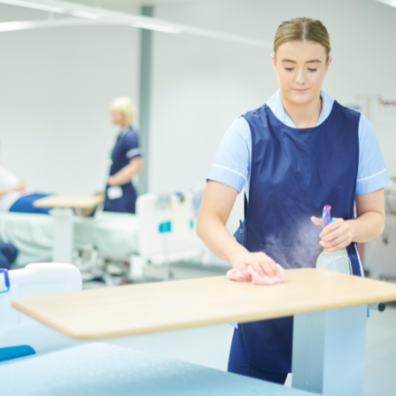 Cleaner wiping down patient area on ward