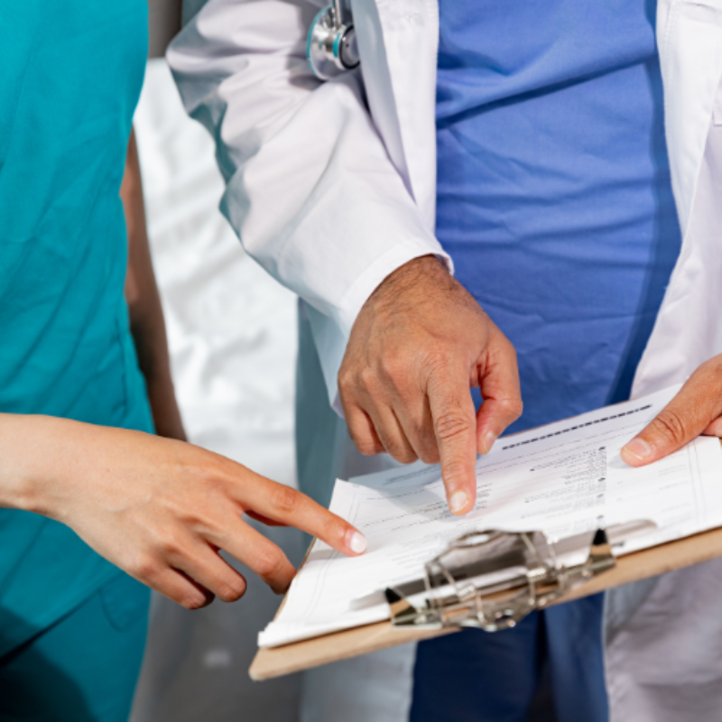 Close up of doctors hands sharing a patient chart and pointing