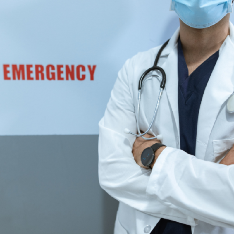 Doctor in lab coat near emergency sign
