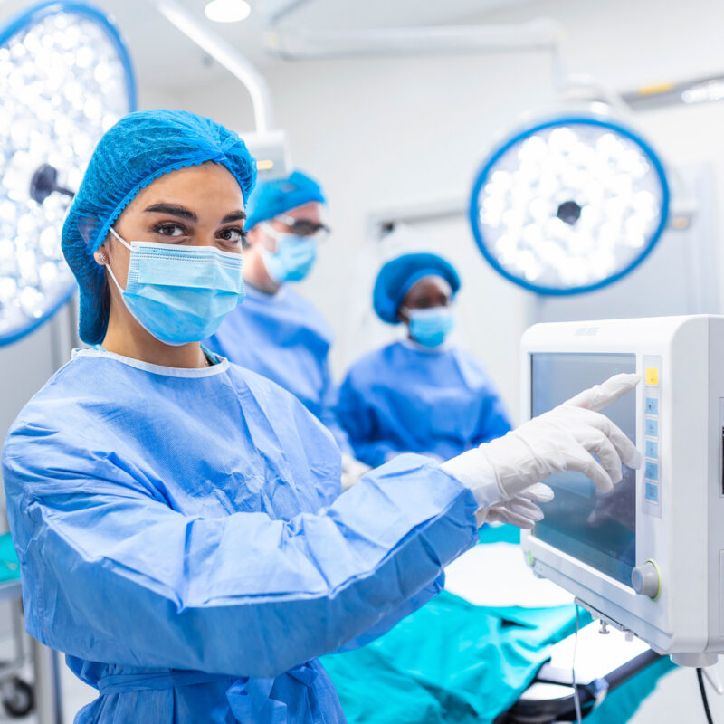 Doctor in surgical gown and mask touching in operating theatre
