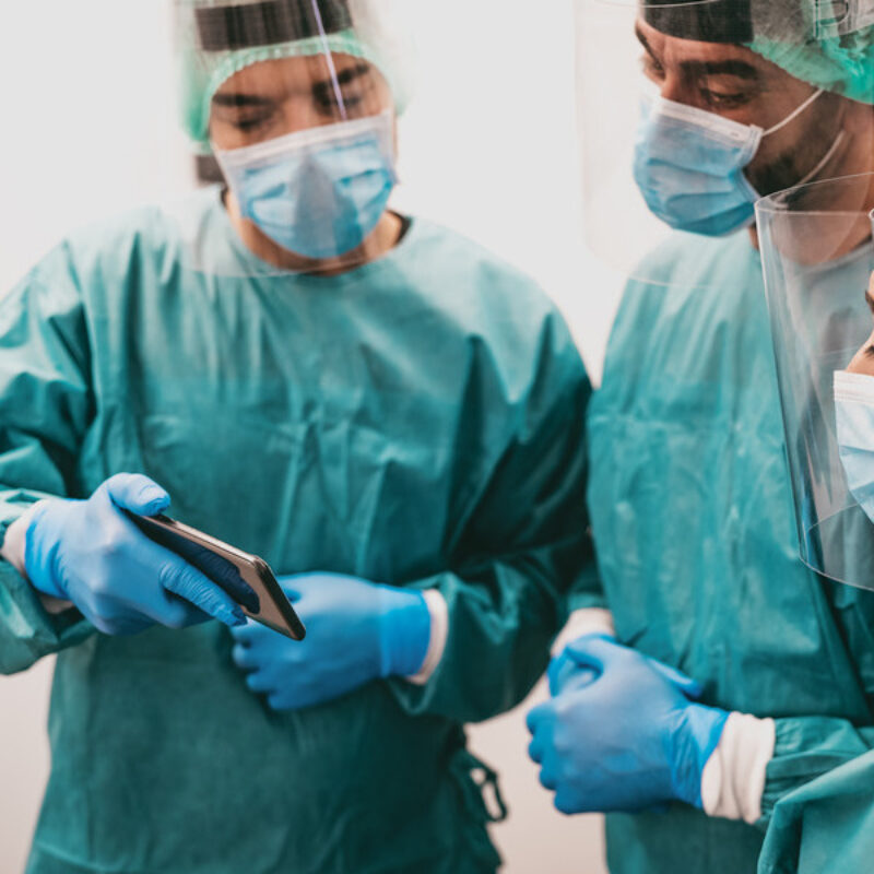 Doctor in surgical scrubs showing another a phone screen
