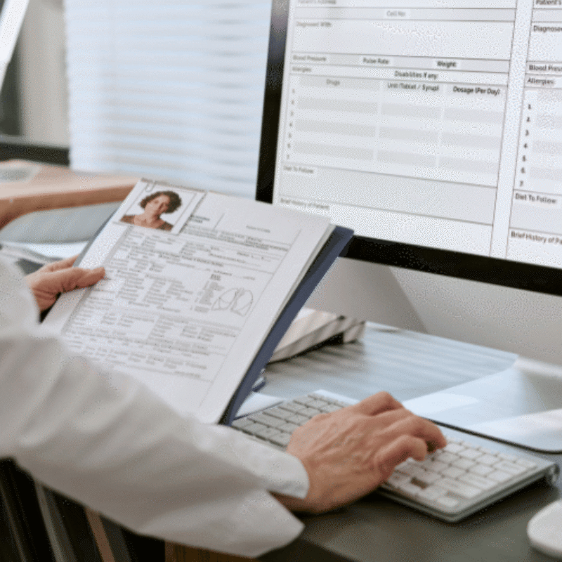 Doctor transcribing paper report into electronic record