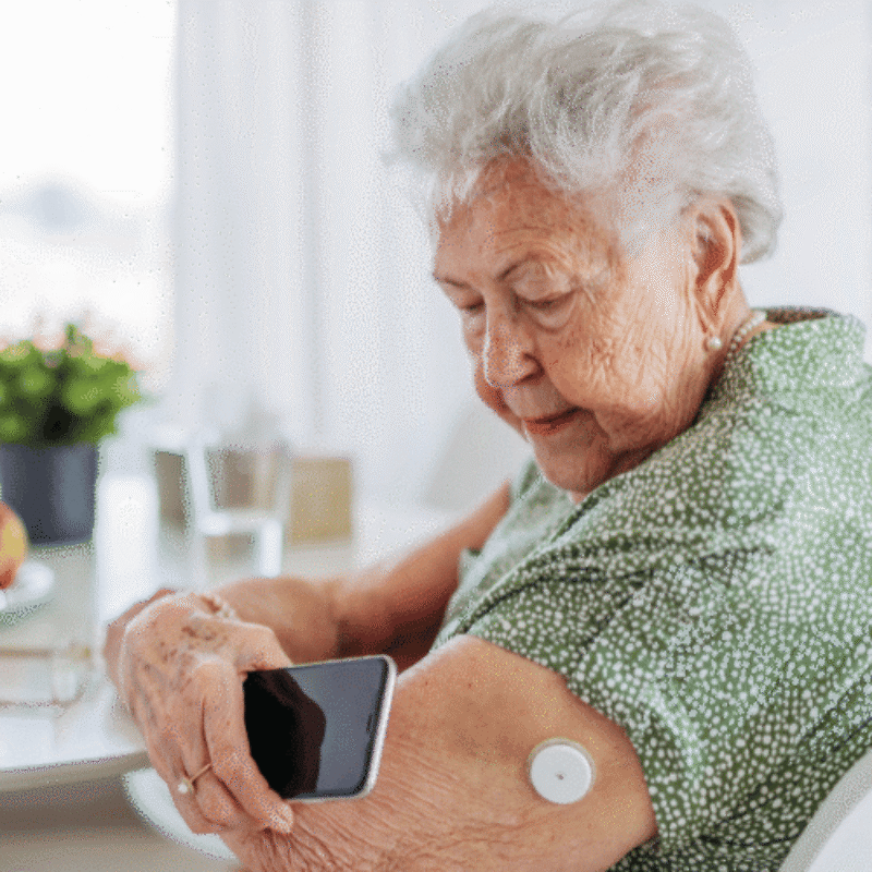 Elderly lady taking photo of sensor on her arm