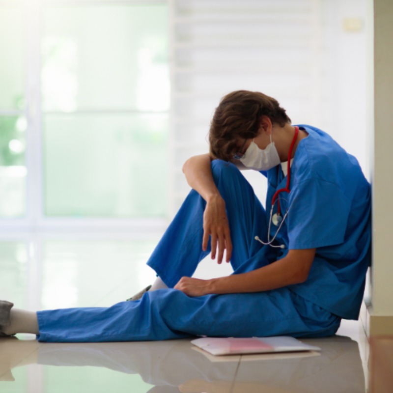 Exhausted young doctor sitting in corridor