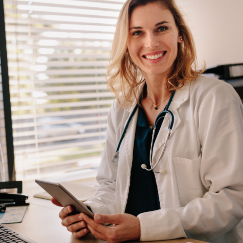 Female doctor smiling to camera holding mobile phone