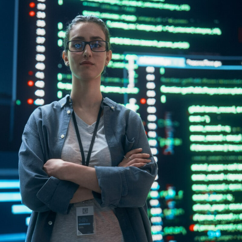 Female information worker in glasses standing in front of data panels