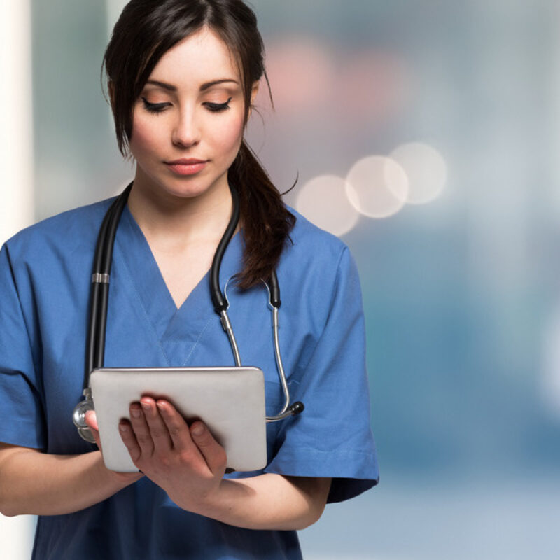 Nurse in scrubs using tablet computer