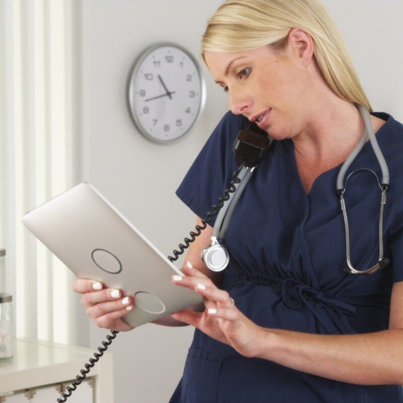 Nurse on landline also holding tablet PC