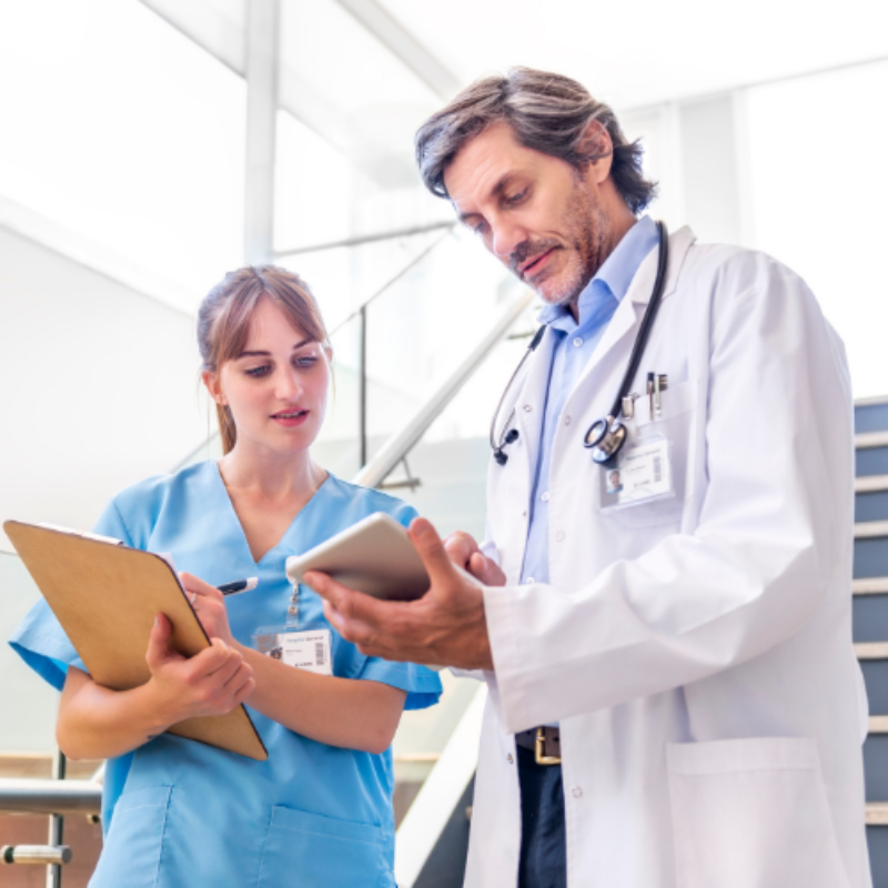 Older male doctor showing younger woman doctor tablet computer