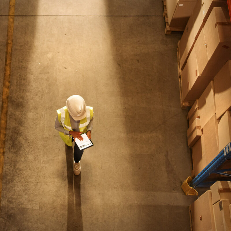 Overhead shot of worker with tablet walking through warehouse