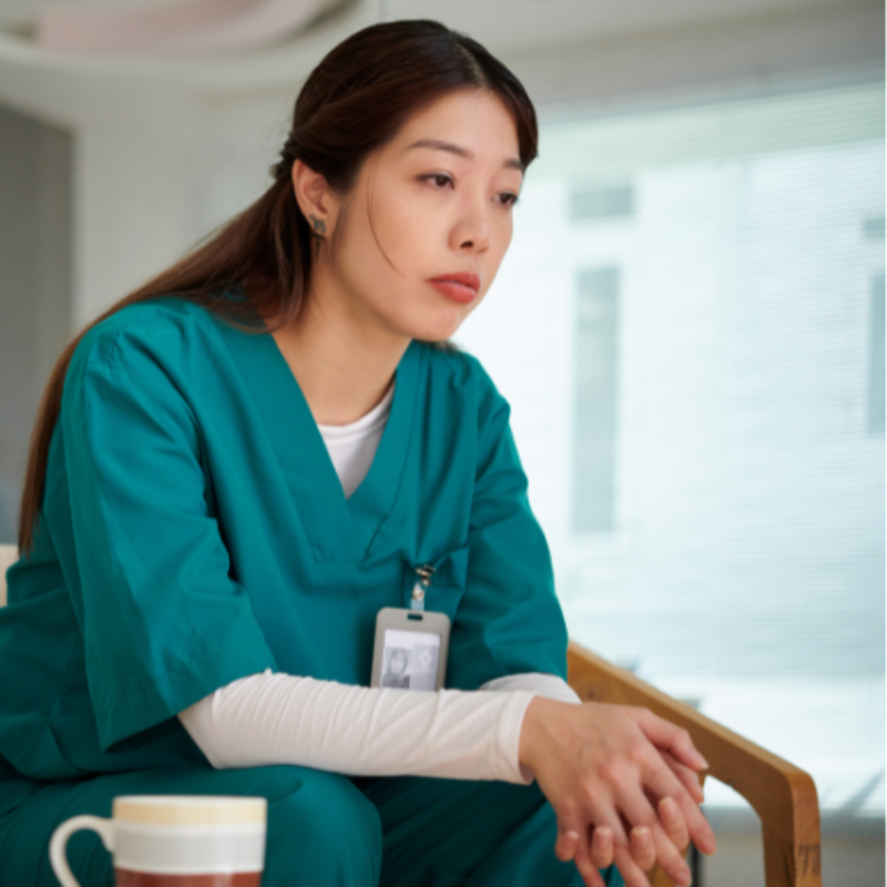 Tired woman nurse in green scrubs in break room