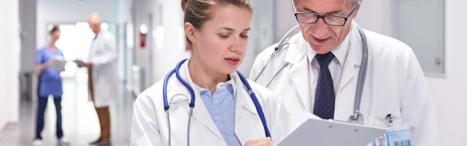 Doctors in lab coats consulting over chart in corridor