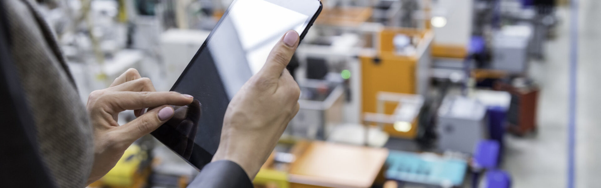 Person using tabelt computer standing above factory floor