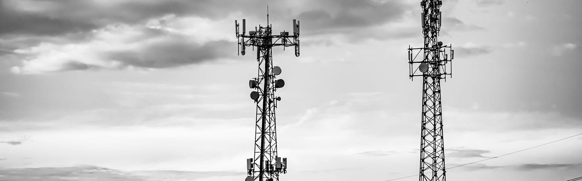 Radio broadcast towers in low light set before a cloudy sky